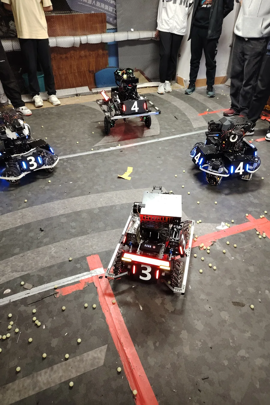 3v3 对抗赛上，己方步兵机器人在场地中列阵，装甲灯亮起，弹丸散落一地
