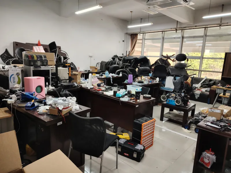 步兵机器人停在实验室零件柜前，麦轮与装甲板清晰可见